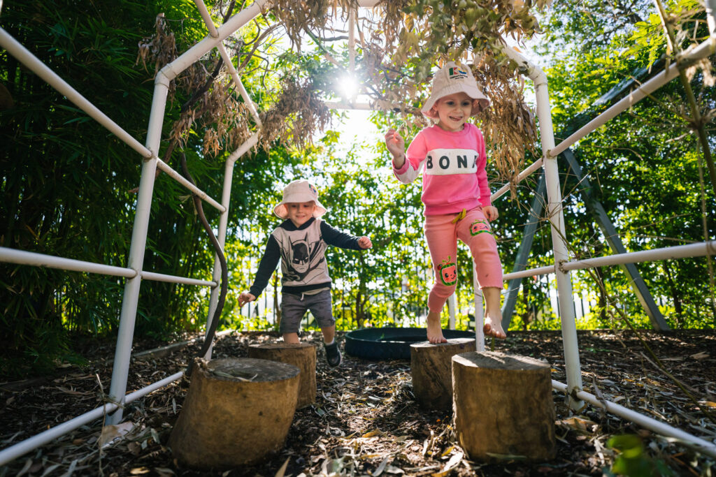 Children hopping from log to log at KU Windale childcare