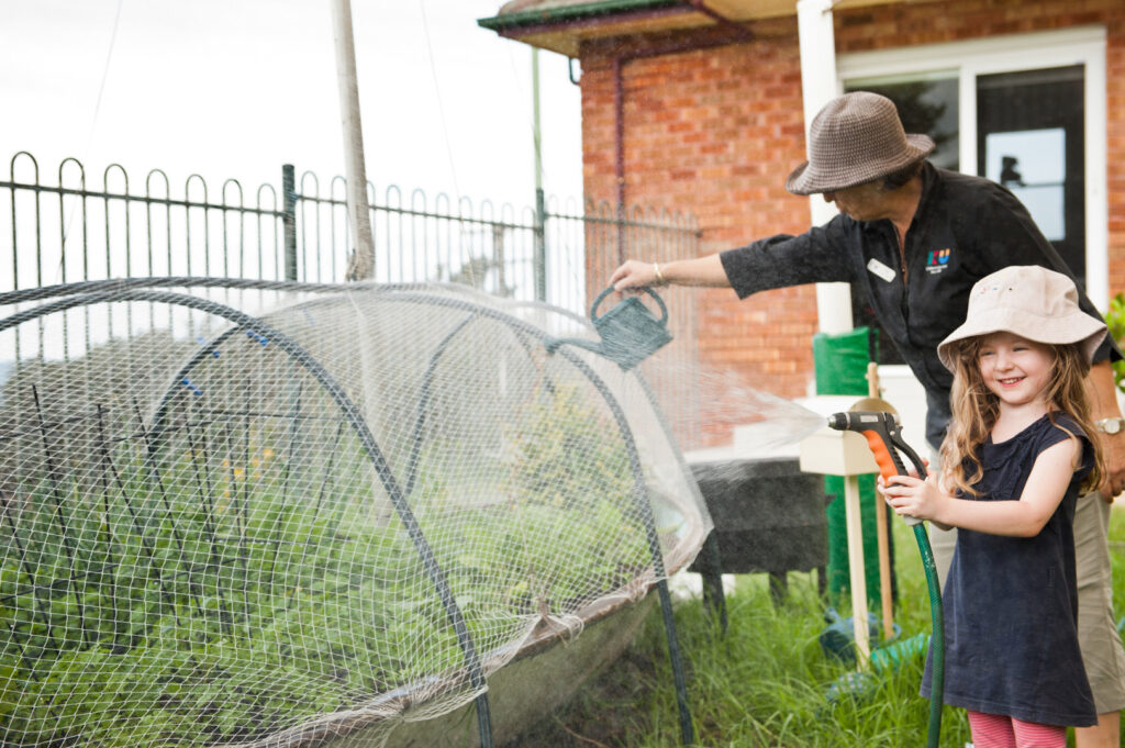 KU Wombarra childcare educator and child watering the garden